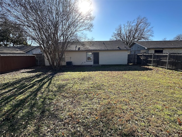 back of house with central AC unit and a lawn