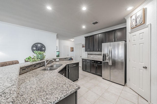 kitchen with crown molding, stainless steel fridge, a kitchen island with sink, and sink