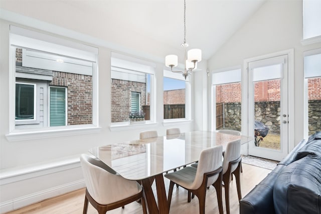 dining area with lofted ceiling, a chandelier, and light wood-type flooring