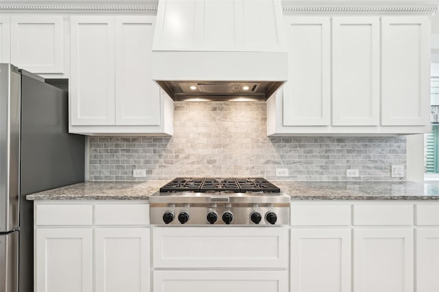 kitchen with white cabinetry, decorative backsplash, stainless steel appliances, and light stone counters