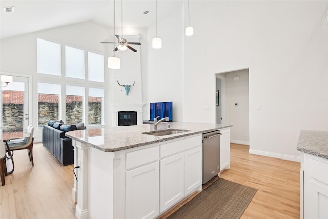 kitchen with sink, decorative light fixtures, stainless steel dishwasher, a kitchen island with sink, and white cabinets