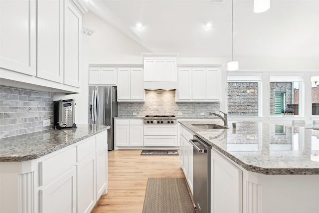 kitchen with white cabinetry, stainless steel appliances, sink, and hanging light fixtures