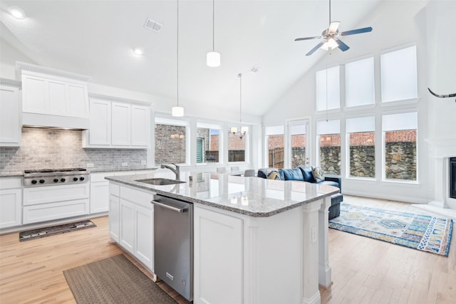 kitchen featuring light stone countertops, a kitchen island with sink, sink, and white cabinets