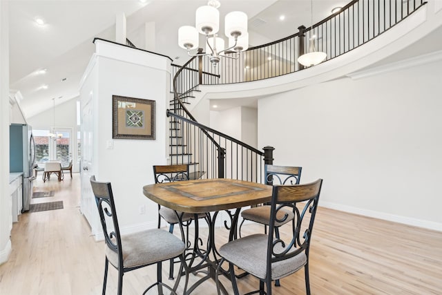 dining area with high vaulted ceiling, a chandelier, and light wood-type flooring