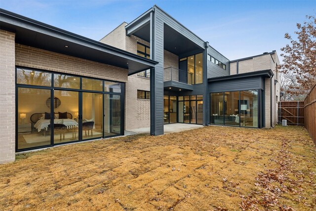 back of property featuring fence, a yard, a patio area, and brick siding
