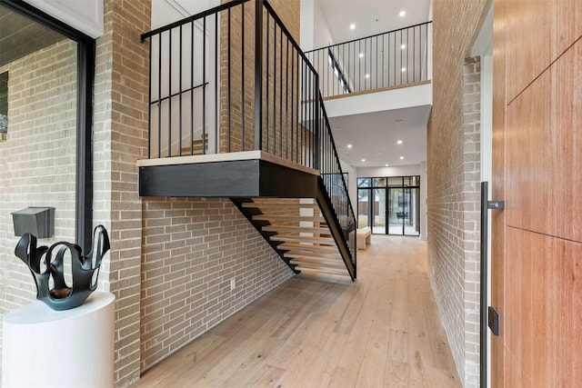 entryway featuring light hardwood / wood-style floors, brick wall, and a high ceiling