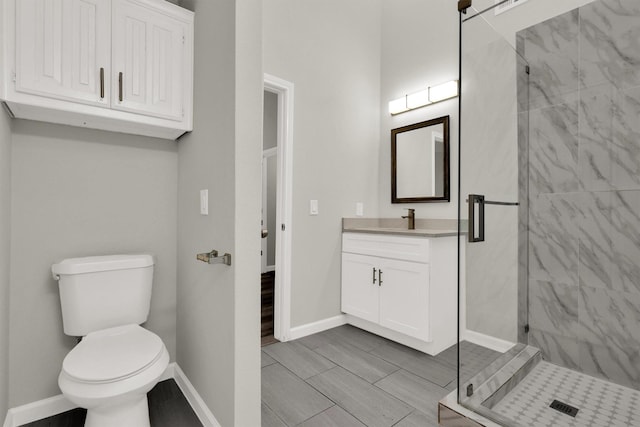 bathroom featuring vanity, a shower with door, and toilet