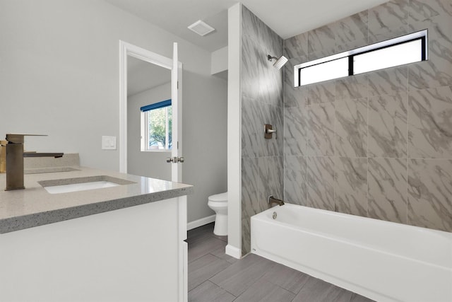 full bathroom featuring tiled shower / bath, vanity, and toilet