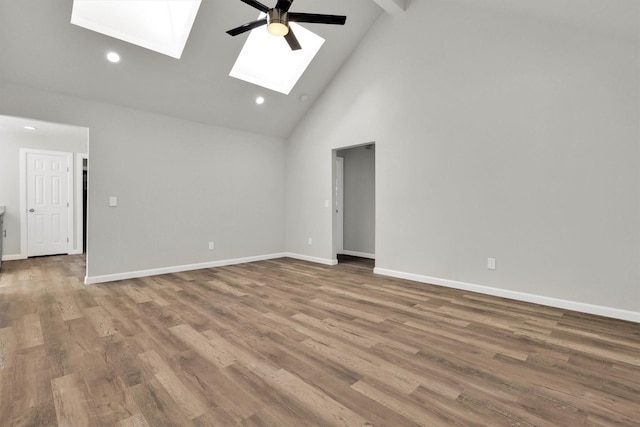 spare room featuring hardwood / wood-style floors, high vaulted ceiling, a skylight, ceiling fan, and beam ceiling