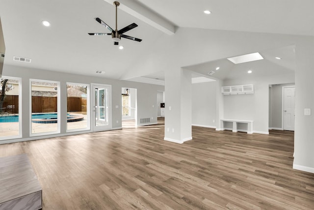 unfurnished living room with hardwood / wood-style flooring, ceiling fan, beam ceiling, a skylight, and high vaulted ceiling