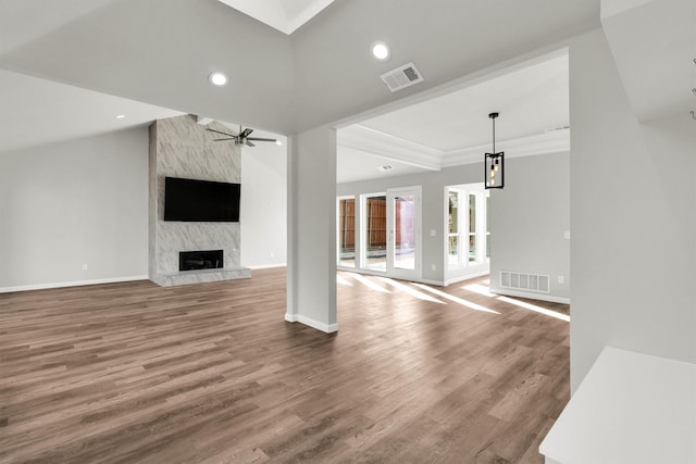 unfurnished living room with hardwood / wood-style floors, crown molding, a premium fireplace, and ceiling fan