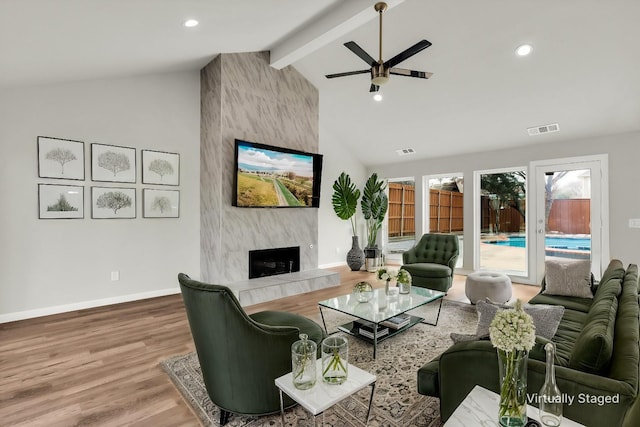 living room with beam ceiling, high vaulted ceiling, ceiling fan, a fireplace, and hardwood / wood-style floors