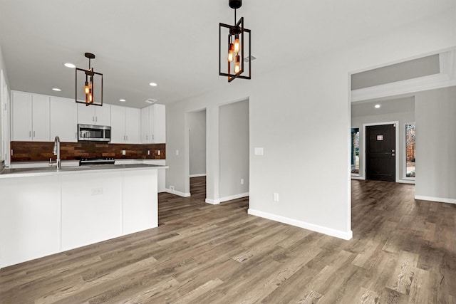 kitchen featuring sink, white cabinetry, pendant lighting, hardwood / wood-style floors, and backsplash