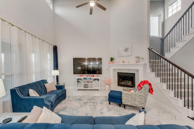 living room with ceiling fan, a fireplace, and a high ceiling