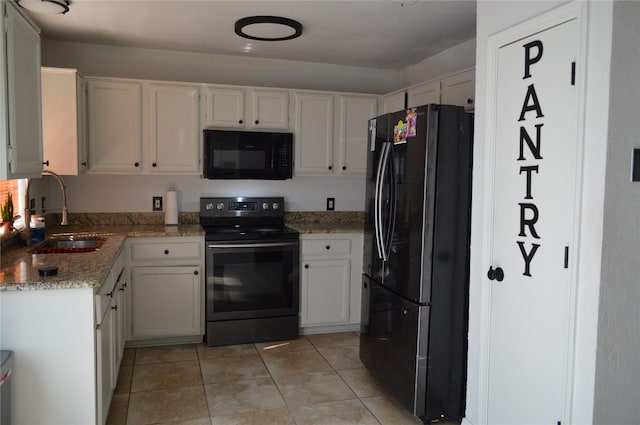 kitchen with light stone counters, sink, black appliances, and white cabinets