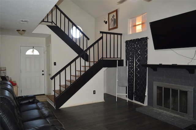 foyer featuring a fireplace, dark hardwood / wood-style flooring, and a high ceiling