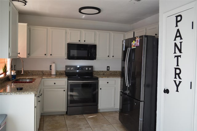 kitchen with light stone counters, sink, black appliances, and white cabinets