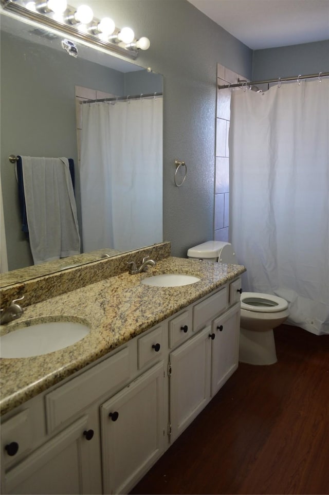 bathroom featuring wood-type flooring, walk in shower, vanity, and toilet