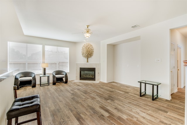 living room featuring ceiling fan, a fireplace, and light hardwood / wood-style floors