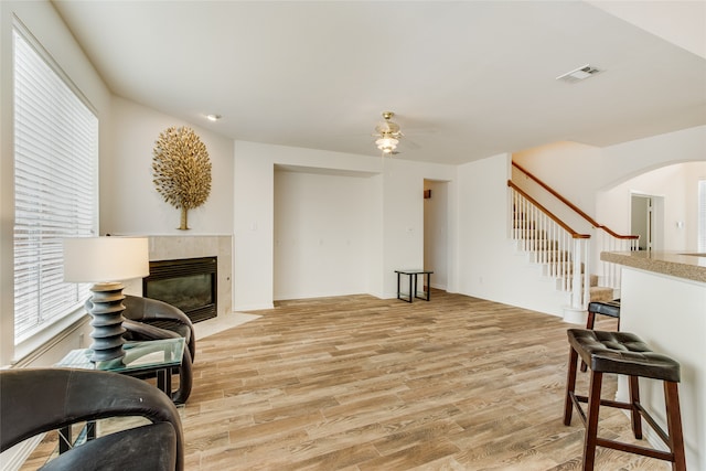 living room featuring a fireplace, light hardwood / wood-style floors, and ceiling fan