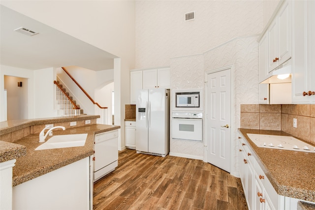 kitchen featuring dark hardwood / wood-style floors, white cabinetry, sink, light stone countertops, and white appliances