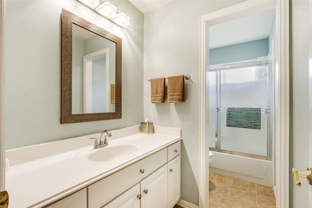 full bathroom with enclosed tub / shower combo, vanity, tile patterned floors, and toilet