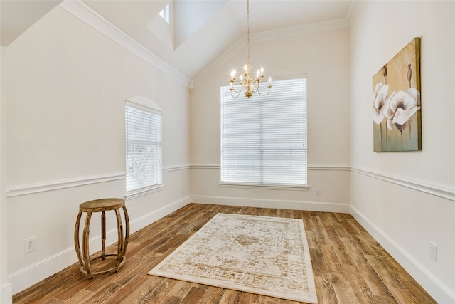 dining space featuring vaulted ceiling, ornamental molding, hardwood / wood-style floors, and a chandelier