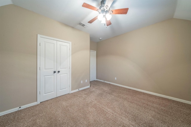 unfurnished bedroom featuring lofted ceiling, light carpet, ceiling fan, and a closet