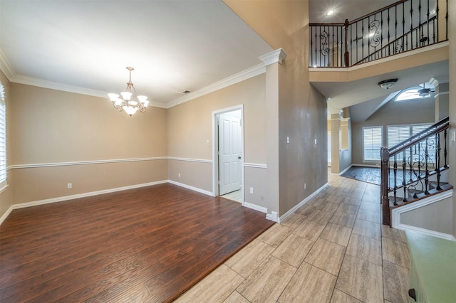 interior space with a towering ceiling, decorative columns, a notable chandelier, wood-type flooring, and ornamental molding