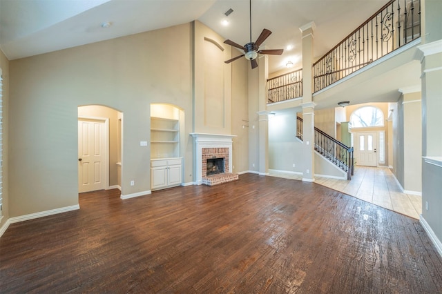 unfurnished living room featuring built in features, ceiling fan, hardwood / wood-style floors, high vaulted ceiling, and a fireplace