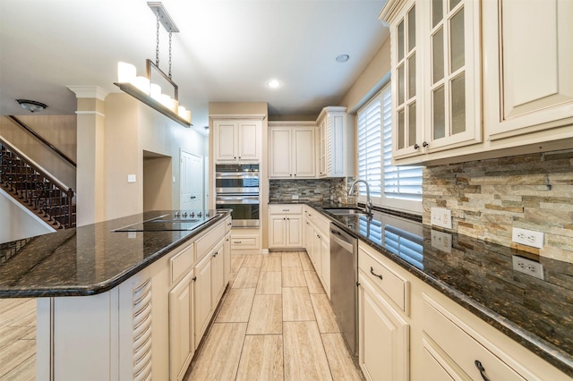 kitchen featuring appliances with stainless steel finishes, sink, dark stone countertops, hanging light fixtures, and a center island