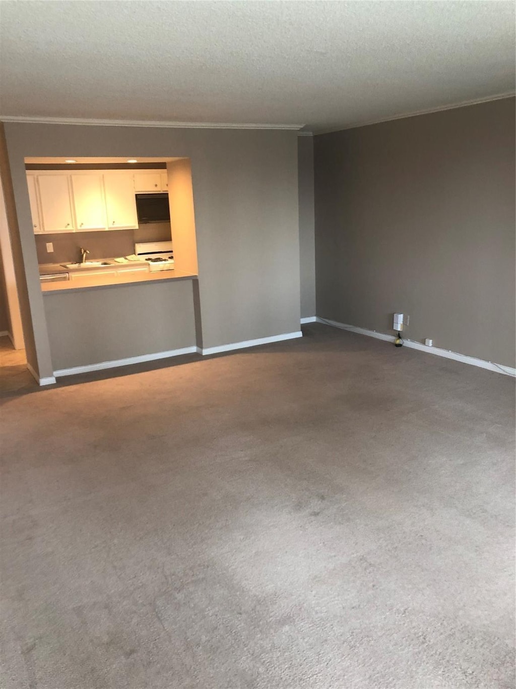 unfurnished living room featuring dark carpet, ornamental molding, and a textured ceiling