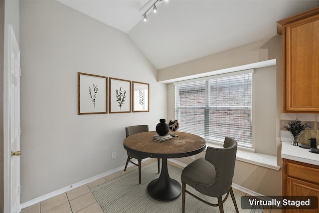 tiled dining room featuring lofted ceiling and rail lighting