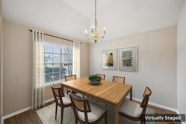 dining room with wood-type flooring, a chandelier, and vaulted ceiling