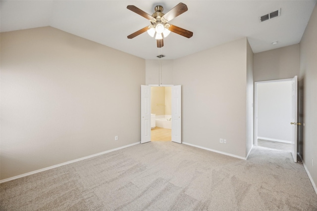 unfurnished bedroom featuring ensuite bath, vaulted ceiling, light colored carpet, and ceiling fan