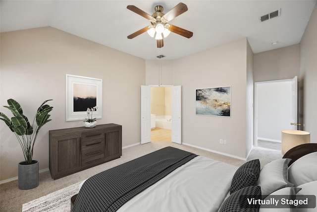 bedroom featuring ceiling fan, vaulted ceiling, light carpet, and ensuite bath