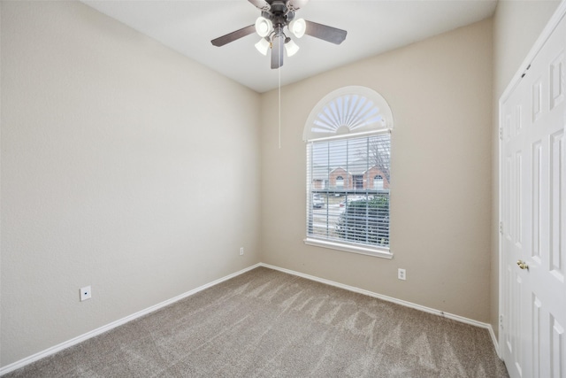 carpeted spare room featuring ceiling fan