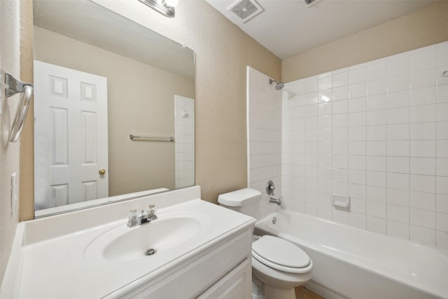 full bathroom featuring vanity, tiled shower / bath, and toilet