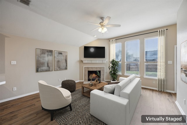 living room featuring hardwood / wood-style flooring, a tile fireplace, vaulted ceiling, and ceiling fan