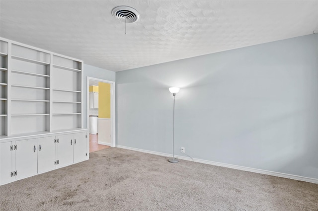 carpeted spare room with built in features and a textured ceiling