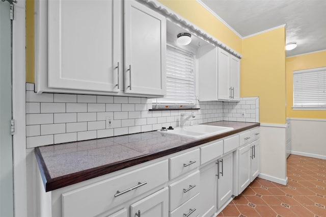 kitchen with tile patterned floors, sink, and white cabinets