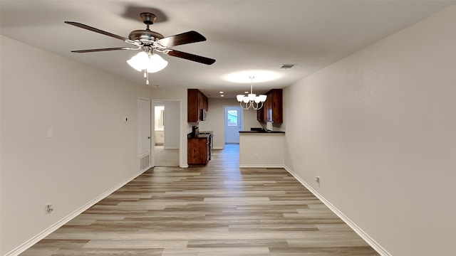 unfurnished living room featuring ceiling fan with notable chandelier and light hardwood / wood-style floors