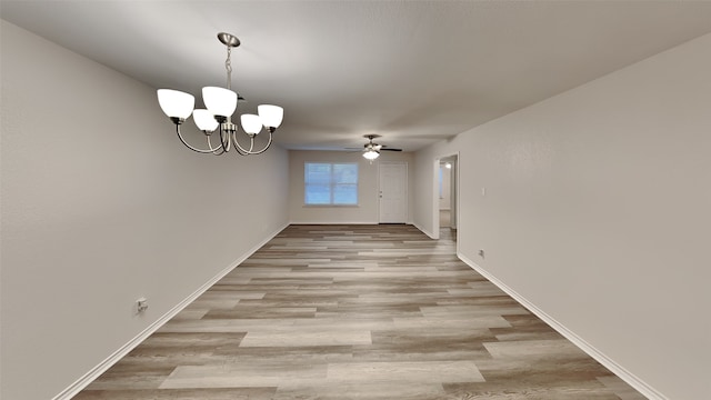 unfurnished dining area with ceiling fan with notable chandelier and light hardwood / wood-style flooring