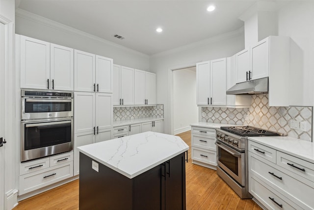 kitchen featuring stainless steel appliances, a center island, light stone countertops, and white cabinets