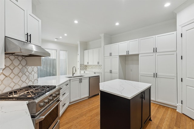 kitchen with sink, light stone counters, white cabinetry, a center island, and appliances with stainless steel finishes