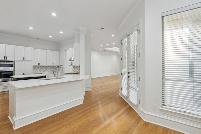 kitchen featuring crown molding, double oven, decorative backsplash, and white cabinets