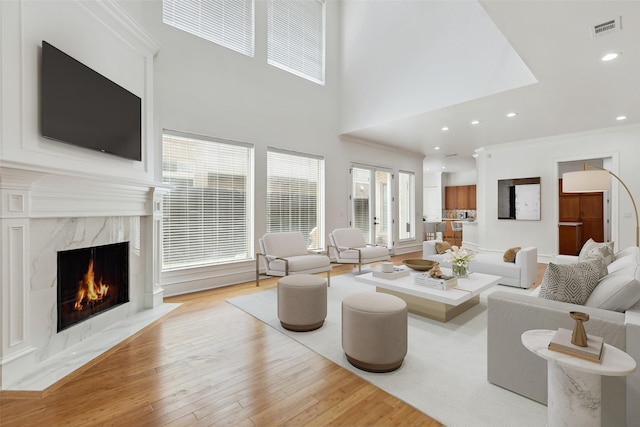 living room with ornamental molding, a fireplace, and light wood-type flooring