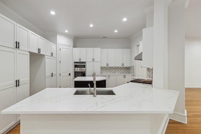 kitchen featuring sink, light stone counters, crown molding, white cabinets, and exhaust hood