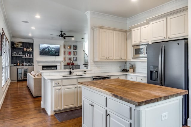 kitchen with appliances with stainless steel finishes, butcher block counters, sink, a center island, and kitchen peninsula