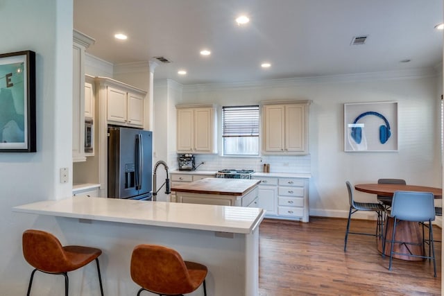 kitchen featuring wood counters, sink, tasteful backsplash, stainless steel fridge with ice dispenser, and ornamental molding